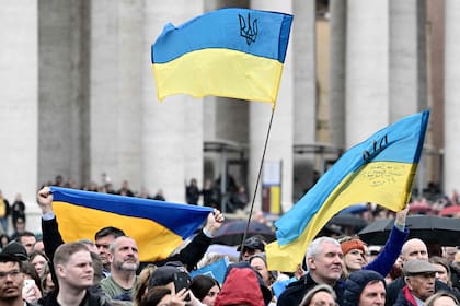 La gente ondea banderas ucranianas en la plaza de San Pedro mientras el Papa Francisco se dirige a la multitud durante su oración del Ángelus dominical el 10 de marzo de 2024 en el Vaticano.